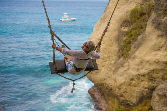 Mature Attractive And Happy Woman On With Grey Hair Enjoying Amazing Sea View From Swing Feeling Young And Free Swinging Carefree Having Beautiful Retirement