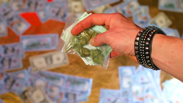 A man is holding a 100 euro bill and a bag of CBD marijuana. The concept of psychological relaxation of personality.