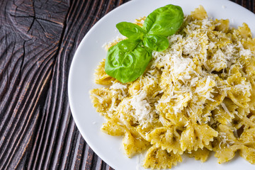 Delicious farfalle pasta with pesto sauce on wooden rustic background