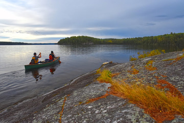 Two paddlers canoe the calm autumn waters of Cirrus Lake in Quetico Provincial Park, Ontario, Canada