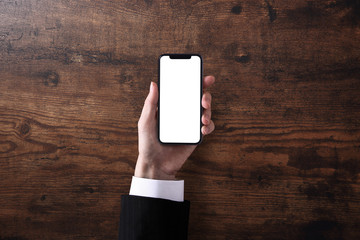 スマホを持つビジネスマン、木のテーブル