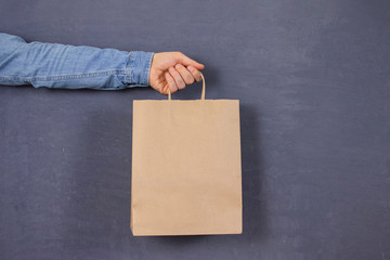 blank craft paper shopping bag mockup, standing in man's hand, fashion advertisement, isolated...