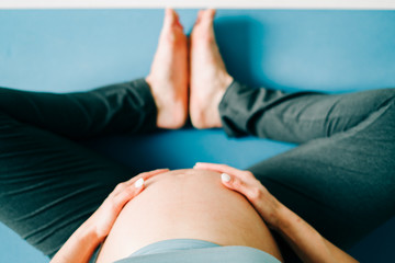 a young pretty pregnant girl in sports clothes is doing yoga, doing asana Baddha Konasana on the Mat, top view