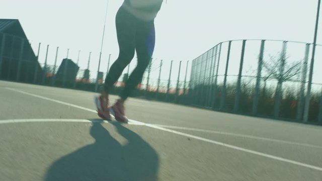 Athletic woman doing icky shuffle on a fenced court in residential area. Action Shot.