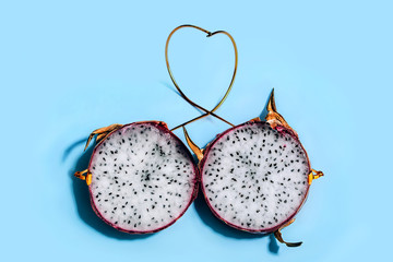 Two slices of Dragon Fruit or Pitaya in skin with golden temples depicting glasses on blue background. Ophthalmology and health concept.