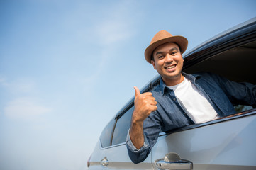 A traveler wearing a hat is driving a car and then pulling himself out of the car window. And...