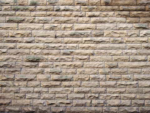 a full frame image of an old yellow sandstone wall made of regular blocks