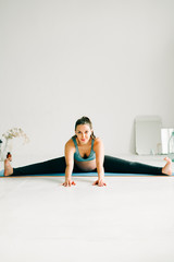 a young beautiful pregnant girl in sports clothes is doing yoga, performing exercises sitting on a rug in the Studio