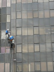 Men working at heights, cleaning building exterior.