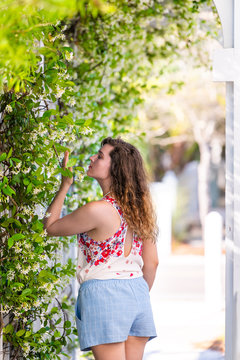 Young Girl Woman In Summer On Sunny Day In Garden Smelling Vine Plant Flowers Outside Wearing Pastel Fashion