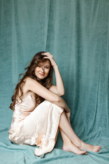 Fototapeta premium happy brunette woman sitting on a green background in a dress.