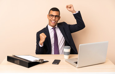 Young business man in his office with a laptop and other documents celebrating a victory