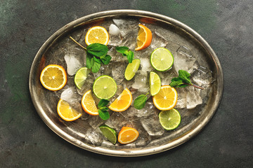 Lime and lemon slices, mint leaves and crushed ice on a metal rustic tray. Top view, flat lay. Ingredients for a cocktail.