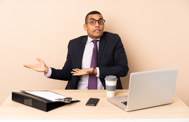 Young business man in his office with a laptop and other documents with surprise facial expression
