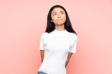 Teenager Chinese woman isolated on pink background and looking up