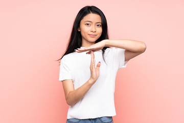 Teenager Chinese woman isolated on pink background making time out gesture