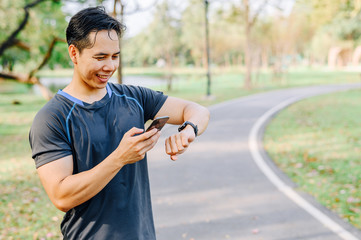 runner checking smart watch on wrist and smartphone
