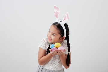 Obraz na płótnie Canvas little child girl with easter bunny ears holding egg