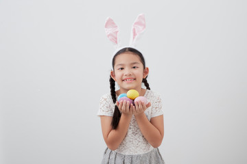 little child girl with easter bunny ears holding egg