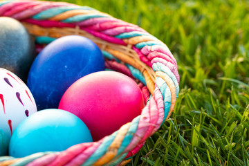 Fototapeta na wymiar Colorful Easter eggs in a wicker basket ina grass field