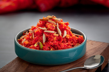 Gajar ka halwa is a sweet dessert pudding from India made from carrot, served in a bowl. Garnished with cashew, almond and pistachio nuts.