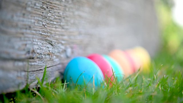 Children's hand takes a colorful easter egg on the lawn. Easter Egg Hunt In Garden Easter concept background.