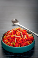 Gajar ka halwa is a sweet dessert pudding from India made from carrot, served in a bowl. Garnished with cashew, almond and pistachio nuts.