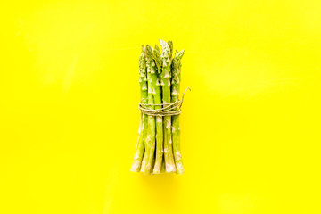 Bunch of asparagus steams on yellow background top-down copy space