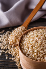 raw brown rice on dark rustic wooden background
