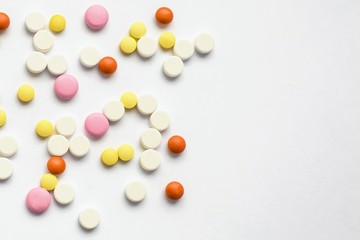 The concept of pills for treatment. Multi-colored white, orange, yellow, pink tablets on a white isolate background . Copy space. Place for text.