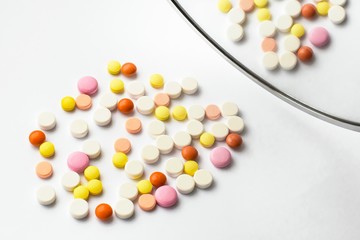 The concept of pills for treatment. Multi-colored white, orange, yellow, pink tablets on a white isolate background and reflection of tablets in the mirror. Copy space