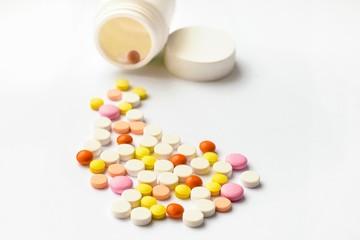 The concept of pills for treatment. Multi-colored white, orange, yellow, pink tablets on a white isolate background. Copy space
