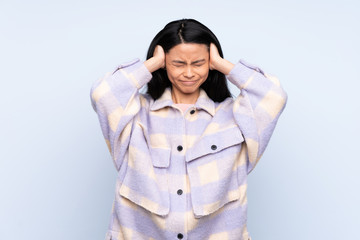 Teenager Chinese woman isolated on blue background frustrated and covering ears