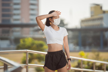 Runners resting tired She wears a nose mask. Protection against dust and viruses