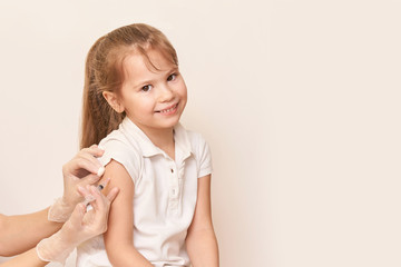 Doctor set shoulder injection to young pretty girl. Kid vaccine medical immunization. Cotton and...