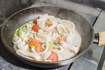 Frying pan with freshly cooked squid in white wine. Tasty and healthy food.