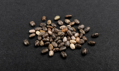 Fototapeta na wymiar Small pile of chia seeds on black background