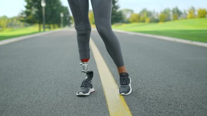 Disabled athlete warming legs before workout in park. Woman training outdoors - Powered by Adobe