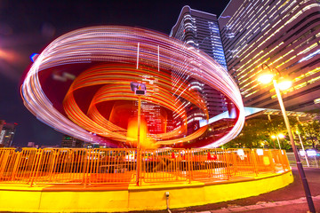 A colorful scenic carousel rotates on itself fast, illuminated at night in Minato Mirai District....