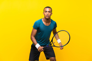 Afro American tennis player man over isolated yellow background © luismolinero