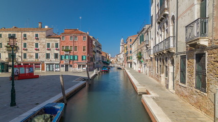 A view of Venice timelapse: canal, bridge, boats and an old tower in the background