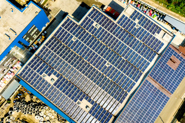 Aerial view of many photo voltaic solar panels mounted of industrial building roof.