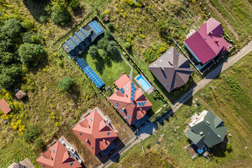 Fototapeta premium Aerial view of rural residential area with private homes between green fields.