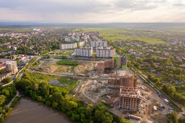 Apartment or office brick buildings under construction, top view. Building site with tower cranes from above. Drone aerial photography.