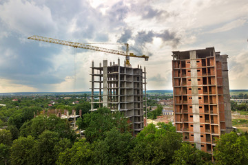 Fototapeta na wymiar Aerial view of tower lifting crane and concrete frame of tall apartment residential buildings under construction in a city. Urban development and real estate growth concept.