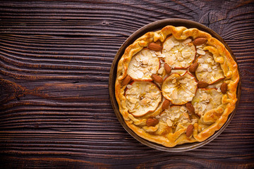 crispy apple galette with almonds on rustic wooden background