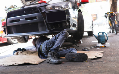 A mechanic crawling under a vehicle which under scheduled maintenance 