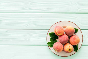 Summer fruits. Ripe red peaches on plate on green wooden table top-down copy space