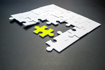 One yellow puzzle among white on a black background