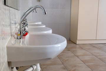 White ceramic washing basins with shiny stainless steel water tap.